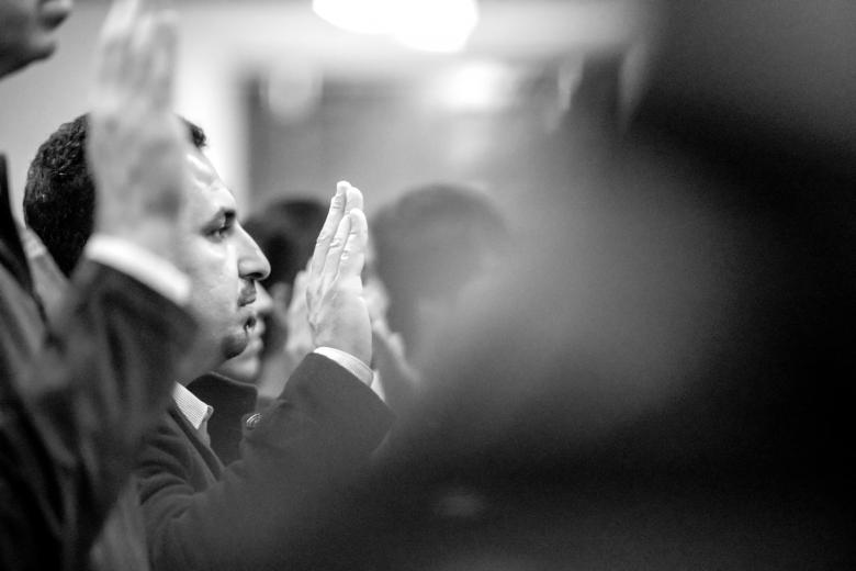 Khaleel raises his hand to take the oath of U.S. citizenship. More than 1,000 people from 81 countries are sworn in and receive their naturalization certificate.