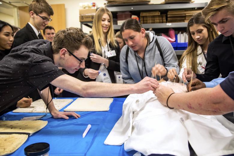 Kyle Boal (left) of Union Mine High School swabs blood stains from a dummy’s coat.