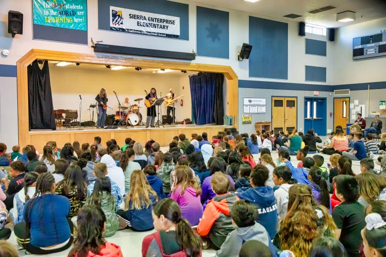 A Blues in the Schools contingent — Ilene McHolland on cello/violin, Larry Schiavone on drums, Lisa Phenix on guitar and Bas Vosen on bass —  performs before about 250 students in April at Sacramento’s Sierra Enterprise Elementary School. (Photo by Steve Martarano)