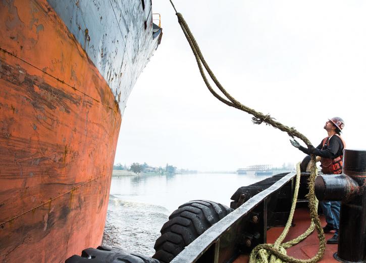 Here, Brusco Tug & Barge deckhand Artie Menosse tightens a line of rope connecting the two ships so the tugboat can guide the larger vessel to shore. “A majority of these ships can stop, but they can’t go sideways or go back and turn, so we put a line on and help guide them into the dock,” says Captain Jeff Hedlund.
Here, Brusco Tug & Barge deckhand Artie Menosse tightens a line of rope connecting the two ships so the tugboat can guide the larger vessel to shore. “A majority of these ships can stop, but they can’t go sideways or go back and turn, so we put a line on and help guide them into the dock,” says Captain Jeff Hedlund.