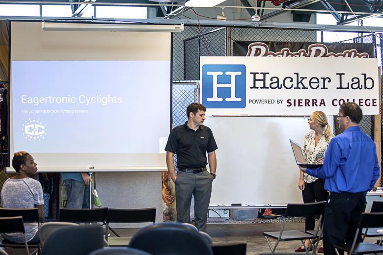 Fellow presenter Peichen Chang, co-founder of Engineered Medical, listens as Adrian and Kelsea Cummings demonstrate their Eagertronics Cyclights bicycle lighting system.