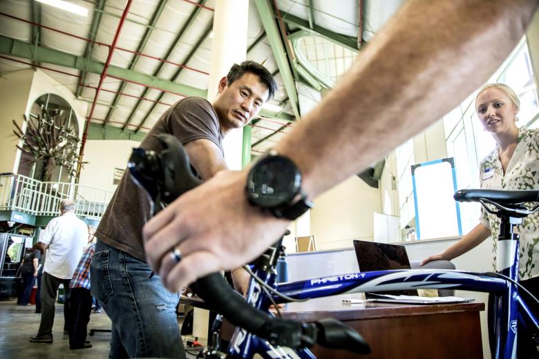 Adrian Cummings demonstrates his invention — a complete lighting system for bicycles — to an attendee at the Startup Hustle final pitch session.