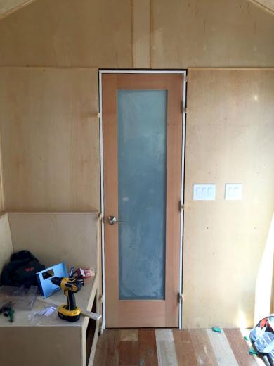 The nearly completed bathroom wall, including a door and built-in seating The nearly completed bathroom wall, including a door and built-in seating