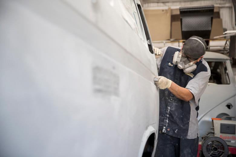 Body restoration technician Miguel Gutierrez sands down the exterior of a 1986 VW van to prep it for painting. Restoration projects, which are often for private collectors or commissions from businesses, can sometimes take years to complete, as the shop collects specialized parts. Kombi Haus has 6-10 Volkswagens in the body shop at any given time.