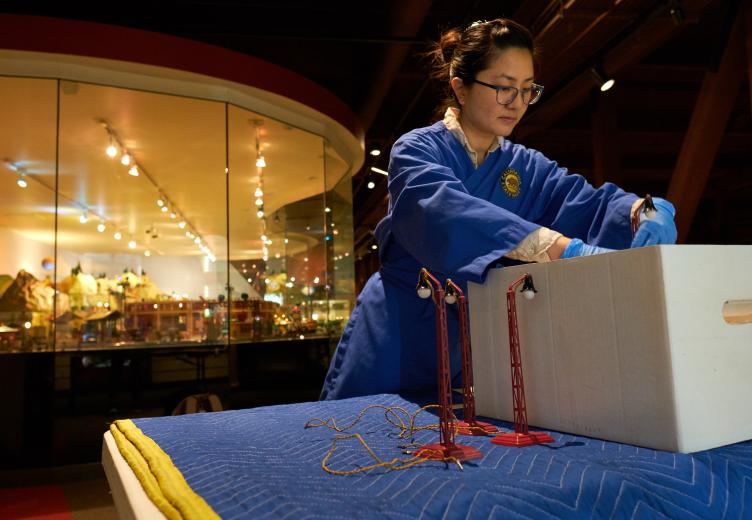 Curator Melanie Tran individually packages tiny street lamps from a newly-donated World War II-era collection, which is being rotated out after being on display since the museum’s Toy Train Month celebration in August.