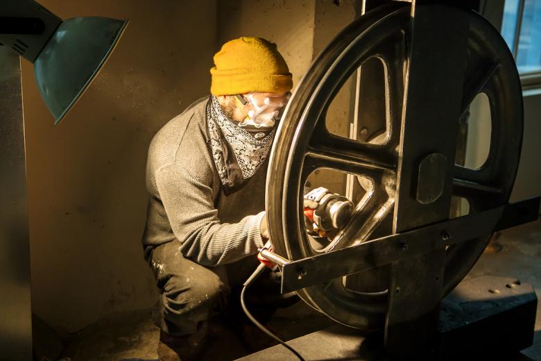 Delgado works into the night to burnish an elevator pulley from the original Lawrence Warehouse that will serve as the centerpiece for his installation Delgado works into the night to burnish an elevator pulley from the original Lawrence Warehouse that will serve as the centerpiece for his installation