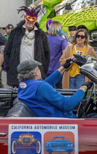 A member of the local California Automobile Museum pauses his cruising to chat with onlookers.