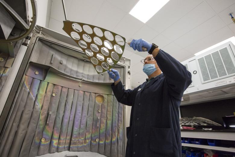 Here, Coating Specialist John Vogt places a panel of lenses into an ultra-high vacuum chamber that will will apply an anti-reflective coating onto the lenses, eliminating glare and allowing wearers to see clearly. Here, Coating Specialist John Vogt places a panel of lenses into an ultra-high vacuum chamber that will will apply an anti-reflective coating onto the lenses, eliminating glare and allowing wearers to see clearly.