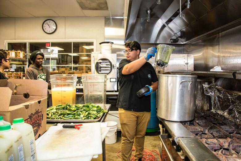 Lopez transfers the pureed jalapenos to a large pot. The full recipe is cooked to temperature before bottling.