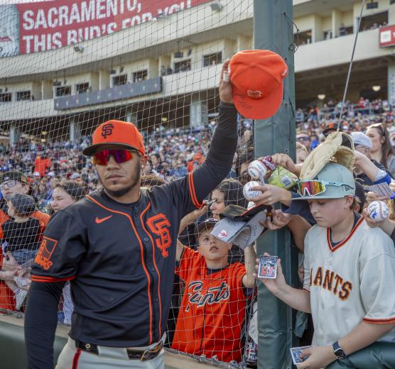 Thairo Estrada, popular when he played in Sacramento, holds up an autographed cap before the game with the River Cats.