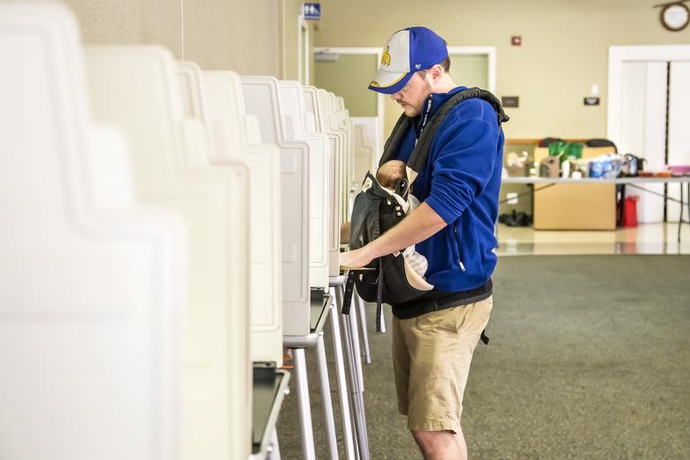Adam Ashton votes while 11-week-old Graham sleeps in his baby carrier. Graham was the youngest visitor to Sierra 2 Center on Election Day.