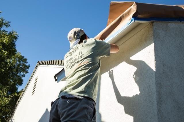 Chis Rica, a volunteer with the Sac State Community Engagement Center, tapes off shingles on the corner of the house. Chis Rica, a volunteer with the Sac State Community Engagement Center, tapes off shingles on the corner of the house.