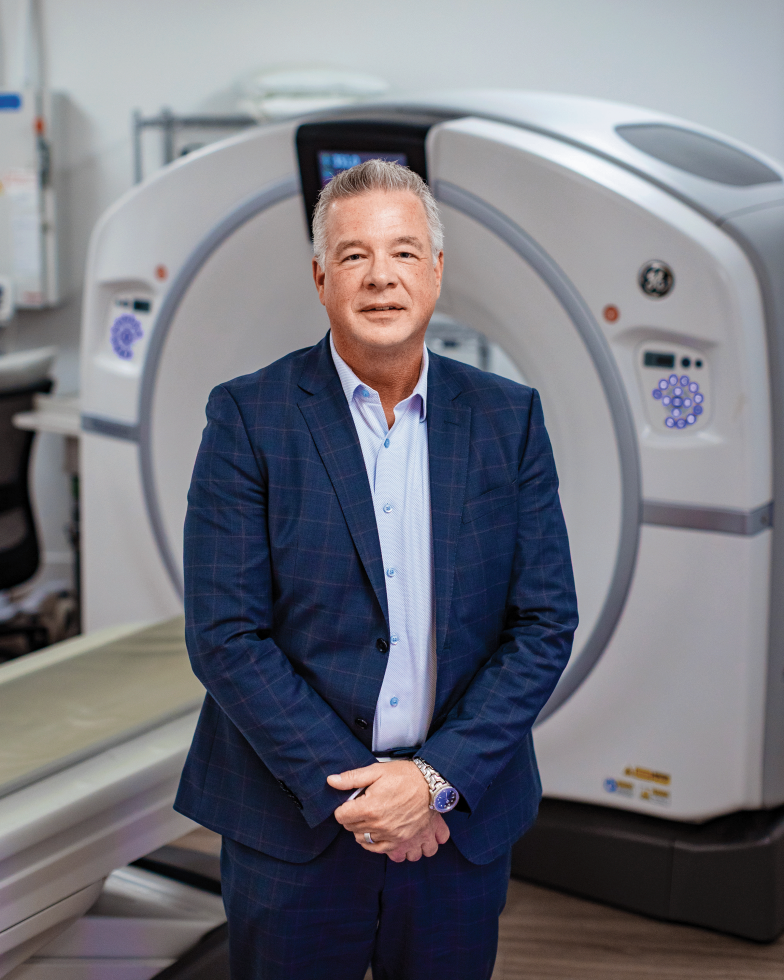 Dignity Health Market President Robert Marchuk stands in front of one of the imaging machines.
